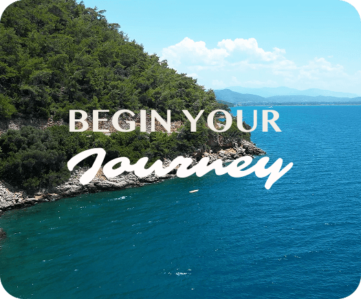 Blue ocean with tree-covered coastline and the words Begin Your Journey overlaid.